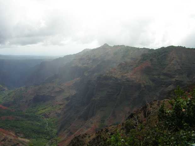 A dark red ridge of craggy hills rises to the right, at its feet a creek runs through green forest, all obscured by mist and fog. A dark red ridge of craggy hills rises to the right, at its feet a creek runs through green forest, all obscured by mist and fog.