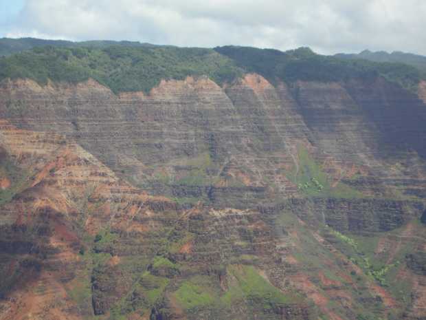Against a distant gray, horizontally banded sheer rock face, a dim grey line runs diagonally from the center down toward the right. Against a distant gray, horizontally banded sheer rock face, a dim grey line runs diagonally from the center down toward the right.